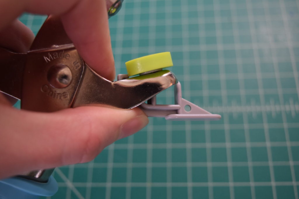 hook the grey piece over the inner edge of the pliers