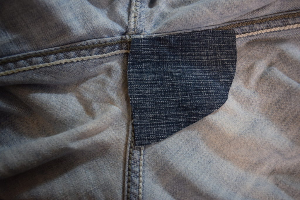 one triangular denim patch is lined up one one side of the back crotch of jeans, fitting between the seams