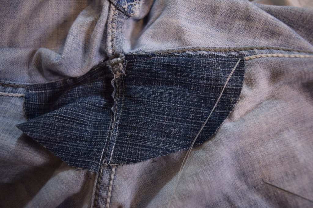 thread is pulled through one end of the patch from the outside of the jeans