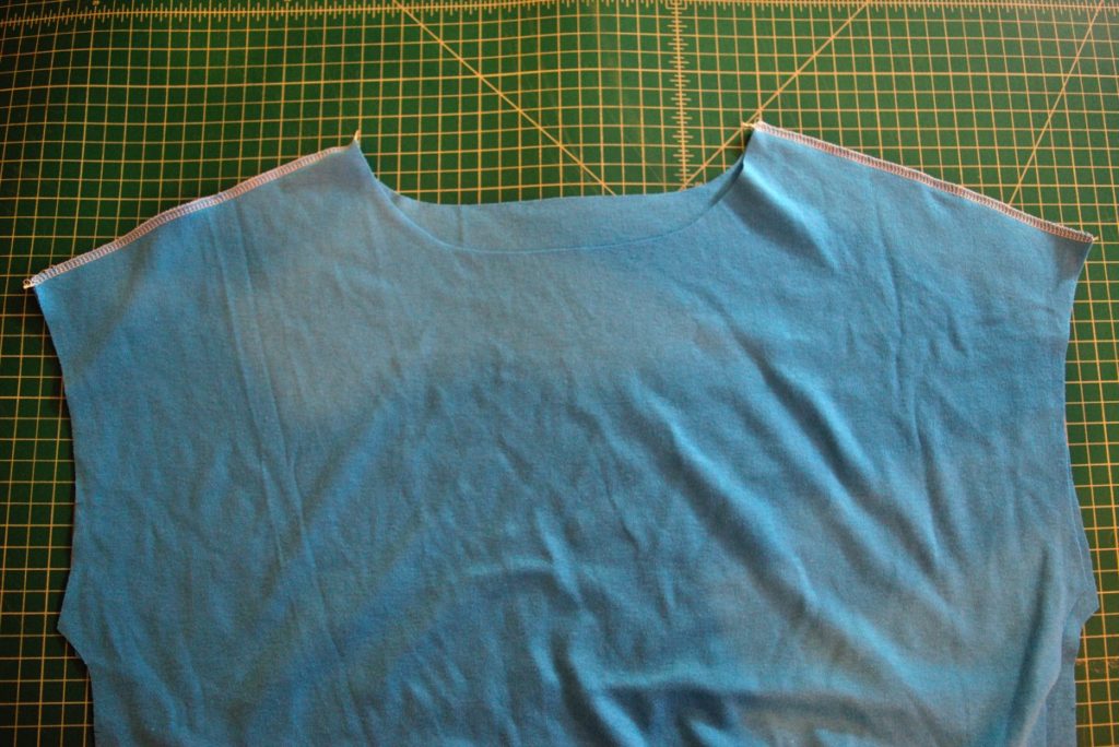 the top portion of a blue kit top with the shoulder seams serger with white thread