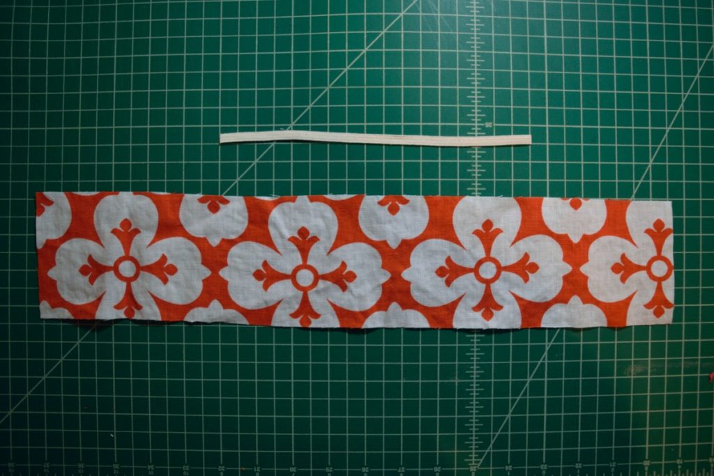 a large rectangle of orange and white fabric with a piece of elastic