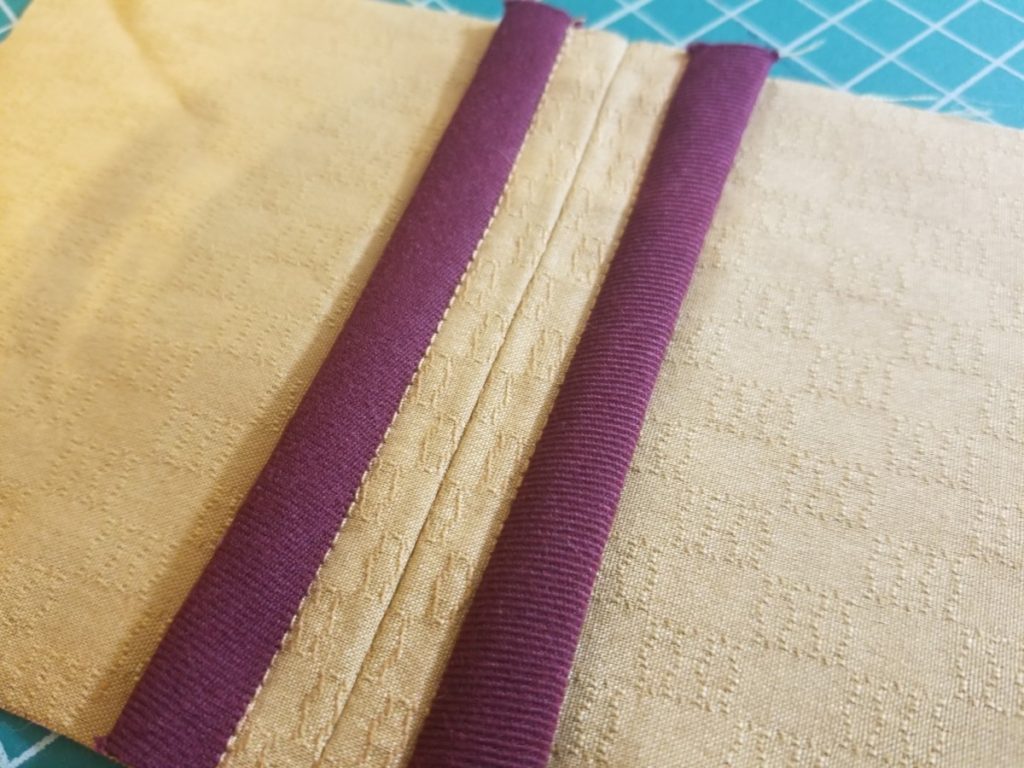 a hong kong seam on mustard fabric with burgundy bias tape