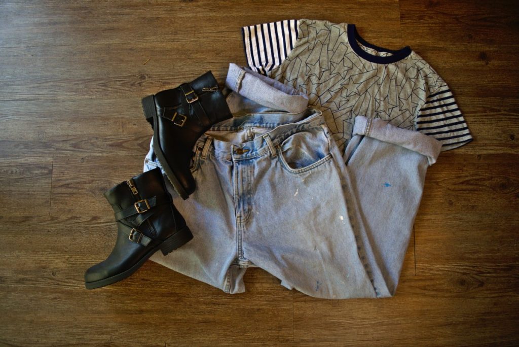 a flatlay of boyfriend jeans, black booties, and a cropped t shirt