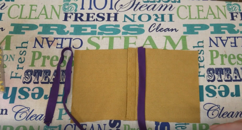 purple bias tape wrapped around the seam of mustard fabric