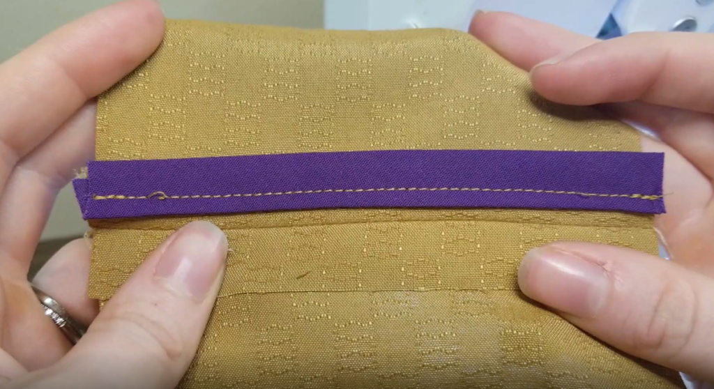 one side of a bias bound seam made from purple bias tape and mustard fabric