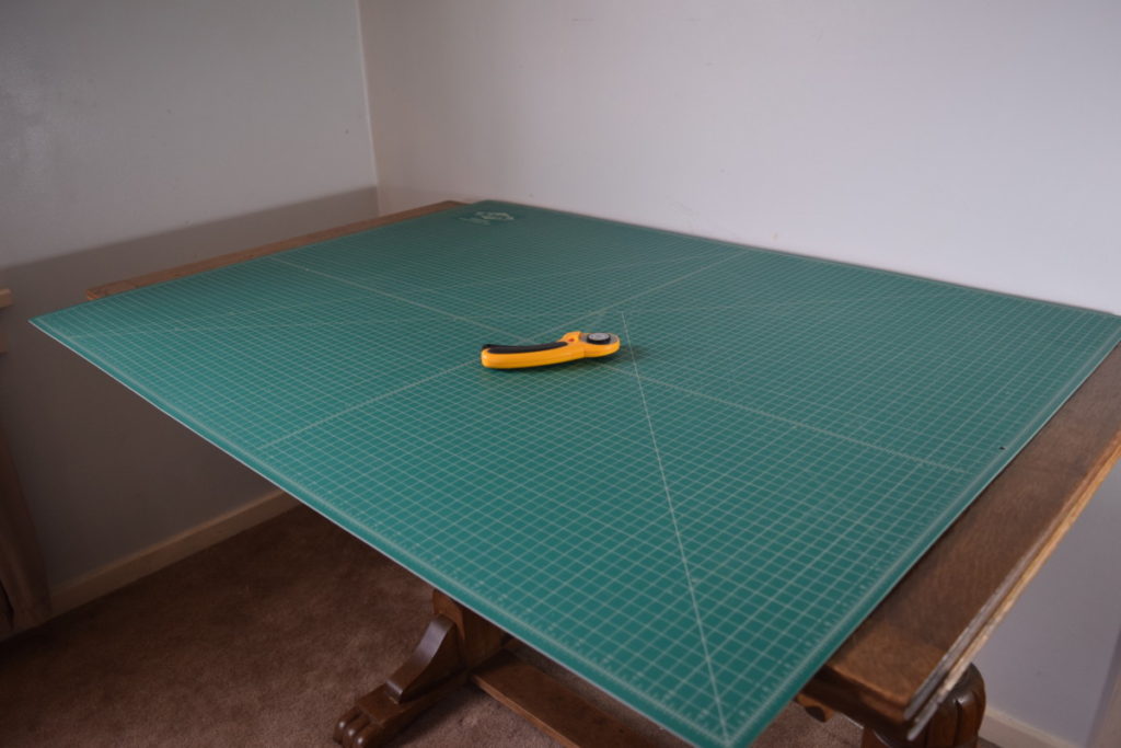 a rotary cutter and mat on a wood table