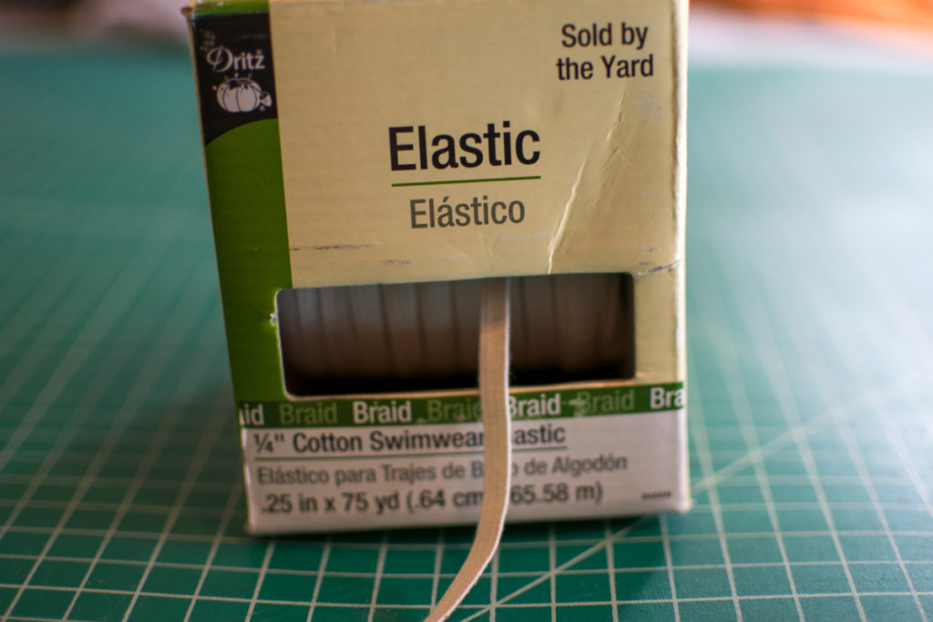 a box containing cotton swimwear elastic is set on a green cutting mat
