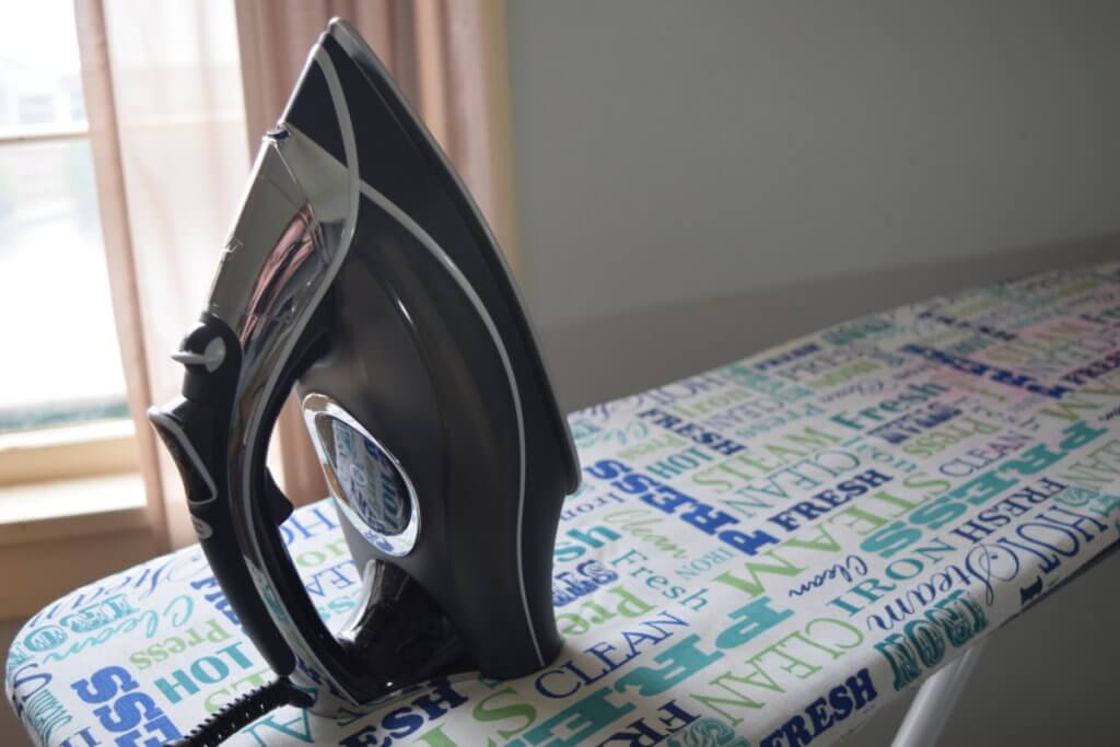 a black and grey iron is sitting on an ironing board in front of a window