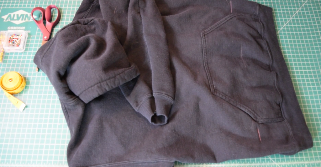 black hoodie on cutting mat with chalk markings on either side of the pocket