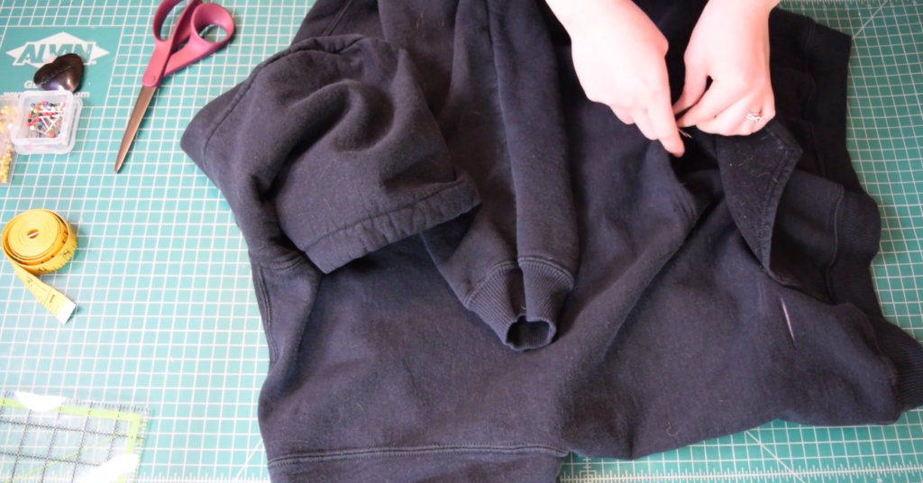 seam ripping the pocket off a black hoodie