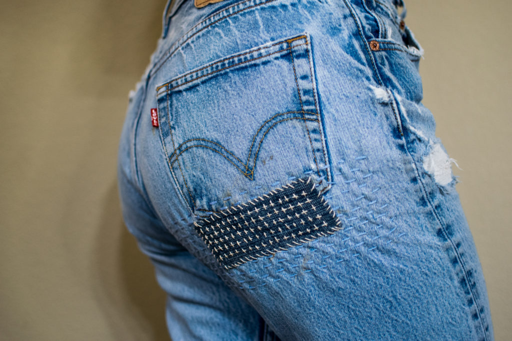 a pair of levi's jeans with a dark denim patch below the back pocket with decorative sashiko stitching across it